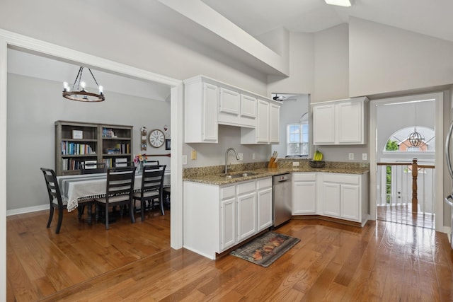 kitchen with a notable chandelier, white cabinets, stainless steel dishwasher, a sink, and wood finished floors