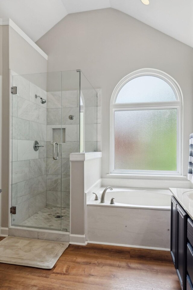 bathroom featuring vanity, a stall shower, lofted ceiling, a garden tub, and wood finished floors