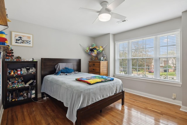 bedroom featuring visible vents, baseboards, a ceiling fan, and hardwood / wood-style flooring