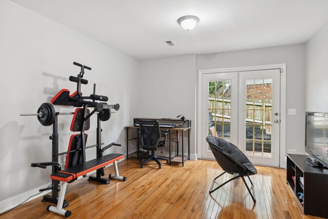 exercise area with baseboards, visible vents, and hardwood / wood-style flooring