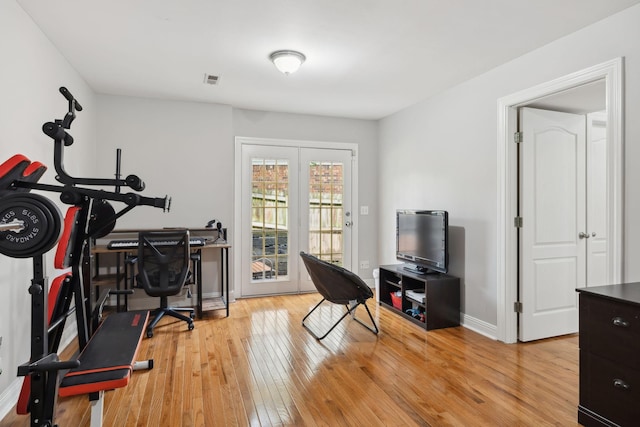 exercise room featuring visible vents, baseboards, and light wood-style floors