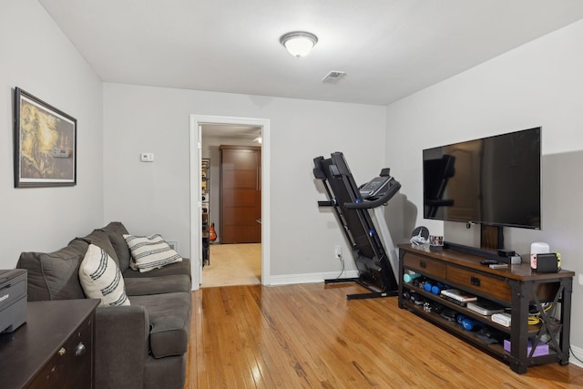 exercise room featuring light wood-style floors, baseboards, and visible vents