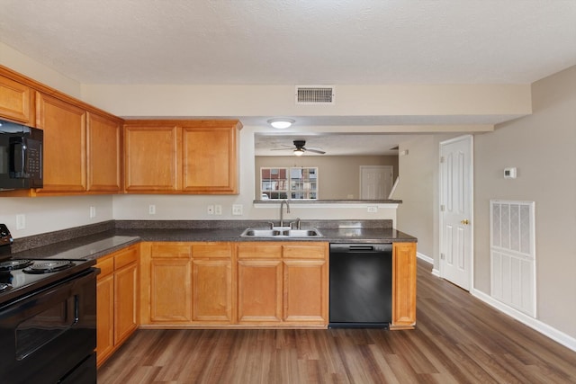 kitchen with visible vents, a sink, dark wood finished floors, and black appliances