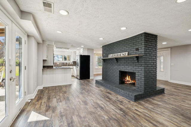 unfurnished living room featuring baseboards, a fireplace, dark wood finished floors, and visible vents