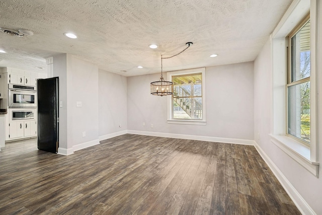 unfurnished dining area with recessed lighting, baseboards, an inviting chandelier, and dark wood finished floors