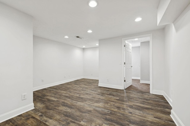 finished below grade area featuring dark wood-style flooring, baseboards, visible vents, and recessed lighting