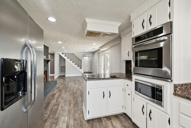 kitchen featuring a peninsula, dark wood-style flooring, white cabinets, and stainless steel appliances