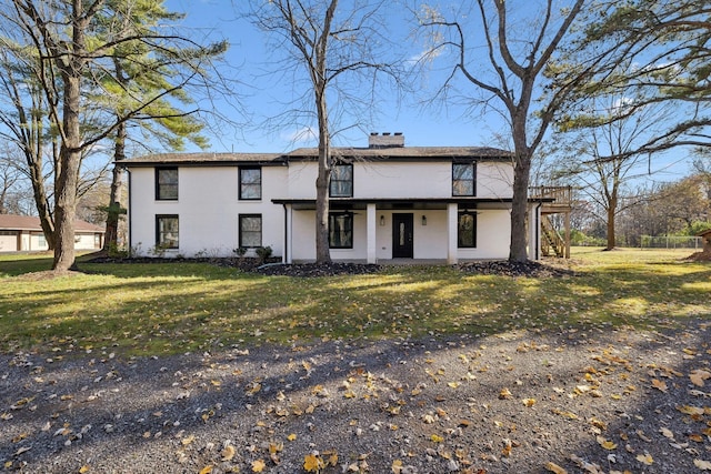 view of front facade featuring a front yard, stucco siding, and a chimney