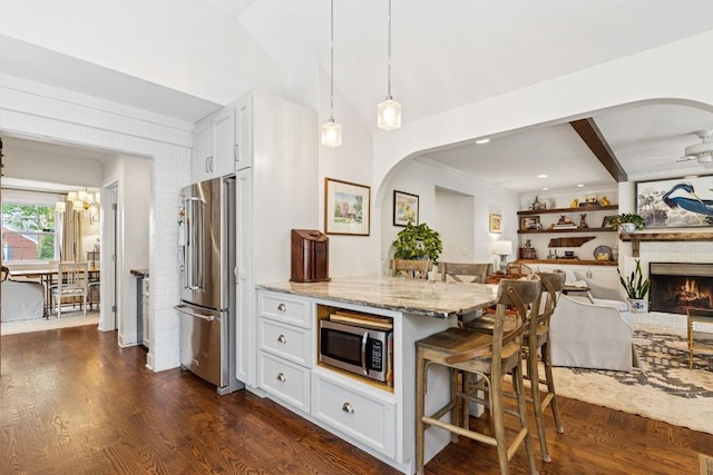 210 Cherokee Rd, Nashville, TN 37205 - kitchen with arched walkways, appliances with stainless steel finishes, a kitchen breakfast bar, white cabinetry, and light stone countertops