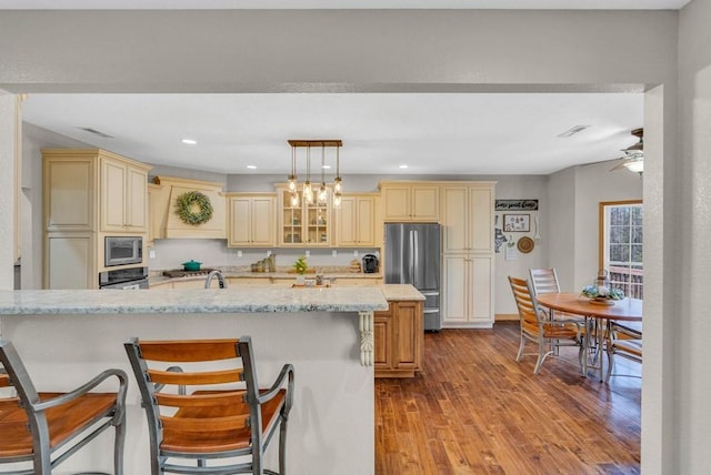 700 Falls Rd, Monterey, TN 38574 - kitchen with dark wood-type flooring, cream cabinetry, appliances with stainless steel finishes, light stone counters, and premium range hood