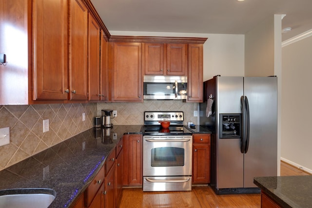 kitchen with light wood-style flooring, tasteful backsplash, brown cabinets, and stainless steel appliances