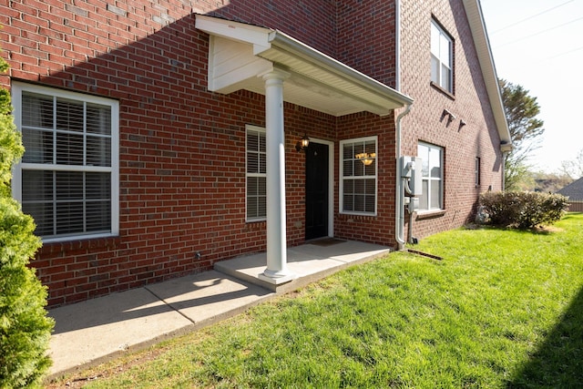 doorway to property featuring a yard and brick siding