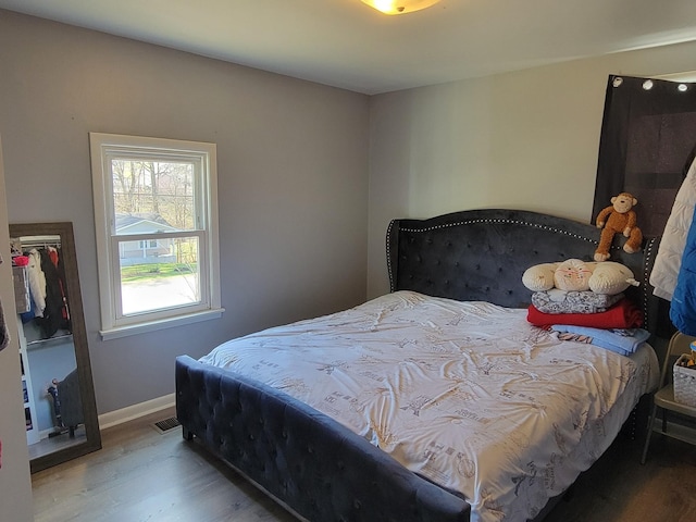 bedroom featuring visible vents, baseboards, and wood finished floors