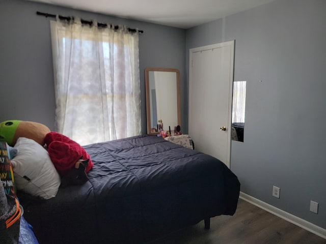 bedroom with baseboards, multiple windows, and wood finished floors