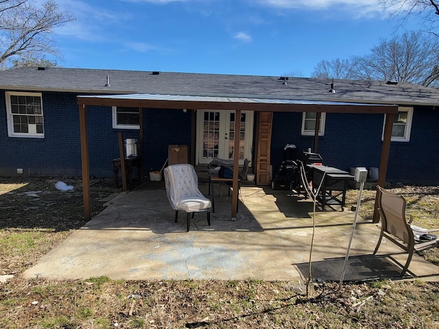 rear view of house featuring crawl space, a patio, roof with shingles, and brick siding