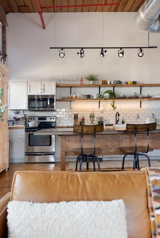 1400 Rosa L Parks Blvd Unit 318, Nashville, TN 37208 - kitchen with open shelves, white cabinetry, wood finished floors, stainless steel appliances, and backsplash