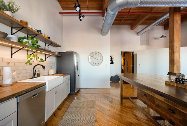 1400 Rosa L Parks Blvd Unit 318, Nashville, TN 37208 - kitchen featuring open shelves, a sink, butcher block counters, a towering ceiling, and stainless steel appliances