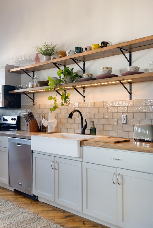 1400 Rosa L Parks Blvd Unit 318, Nashville, TN 37208 - kitchen with stainless steel dishwasher, light wood-style flooring, open shelves, a sink, and backsplash