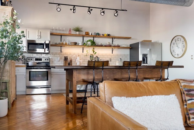 1400 Rosa L Parks Blvd Unit 318, Nashville, TN 37208 - kitchen featuring hardwood / wood-style floors, decorative backsplash, white cabinets, and stainless steel appliances
