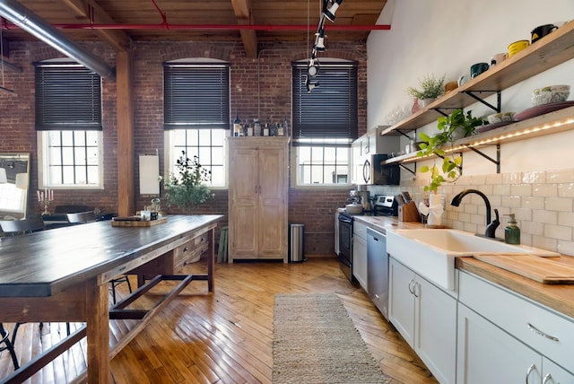 1400 Rosa L Parks Blvd Unit 318, Nashville, TN 37208 - kitchen featuring open shelves, brick wall, a sink, light wood-type flooring, and stainless steel appliances