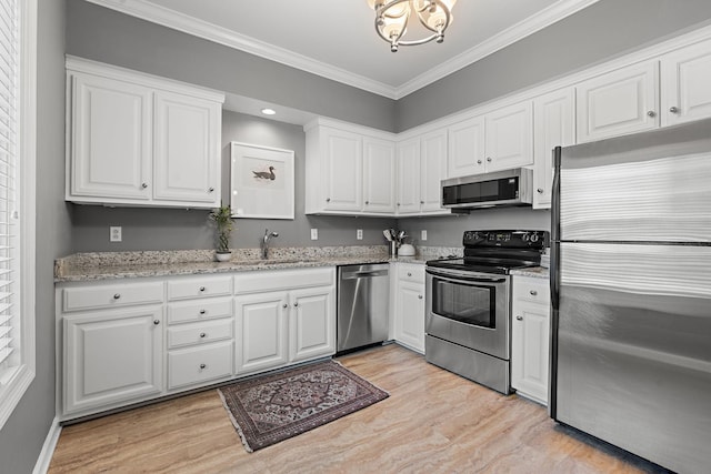 kitchen with a sink, ornamental molding, appliances with stainless steel finishes, and light wood-style floors