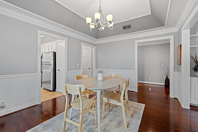 dining area featuring visible vents, a raised ceiling, wood-type flooring, and a notable chandelier
