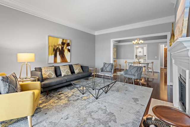 living room with a chandelier, a glass covered fireplace, crown molding, and wood finished floors