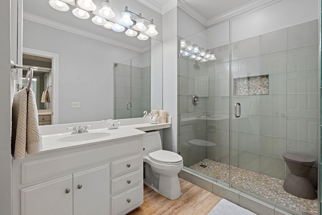 bathroom with toilet, crown molding, wood finished floors, and a stall shower