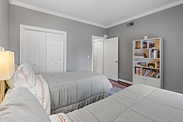 bedroom with a closet, ornamental molding, visible vents, wood finished floors, and baseboards