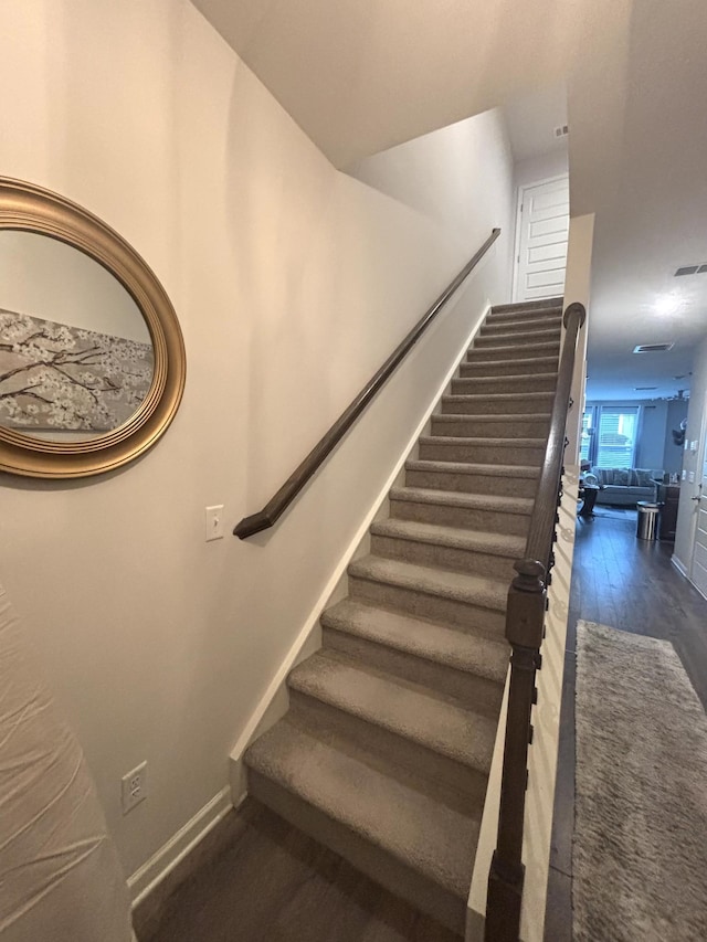 staircase with wood finished floors and visible vents