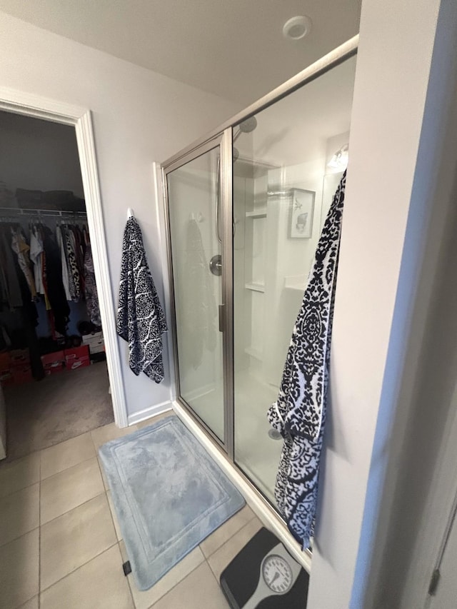 full bathroom featuring tile patterned floors, a walk in closet, and a stall shower