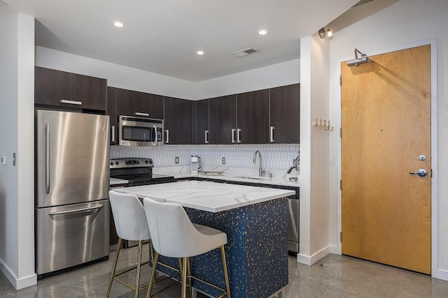600 12th Ave S Unit 521, Nashville, TN 37203 - kitchen featuring visible vents, a breakfast bar, appliances with stainless steel finishes, a sink, and decorative backsplash