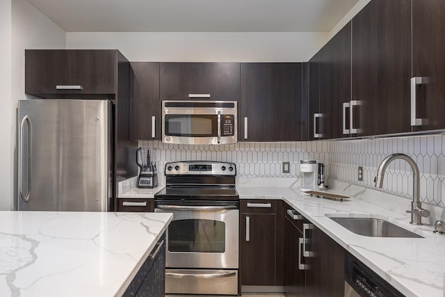 600 12th Ave S Unit 521, Nashville, TN 37203 - kitchen with a sink, dark brown cabinets, stainless steel appliances, decorative backsplash, and light stone counters