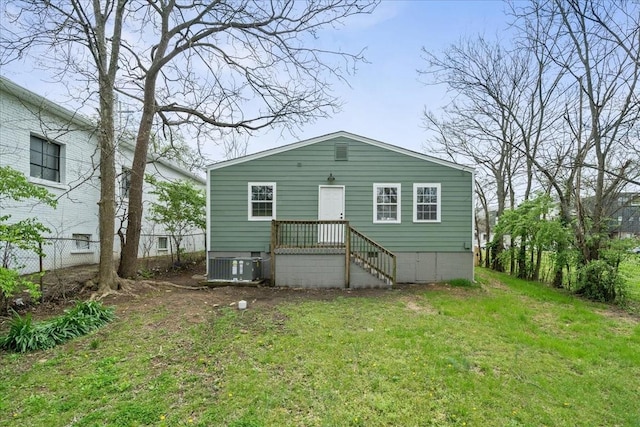 rear view of house with cooling unit, fence, and a lawn