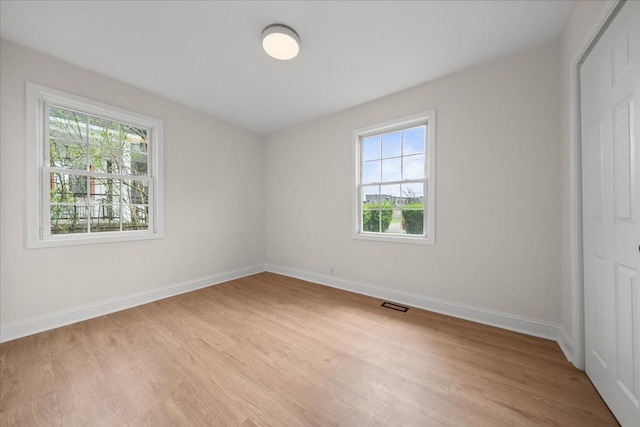 unfurnished room featuring light wood-style floors, baseboards, and visible vents