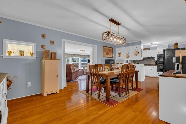 dining room with light wood finished floors and crown molding