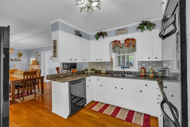 kitchen with black appliances, light wood-style flooring, a sink, and crown molding