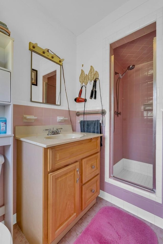 bathroom with a shower stall, vanity, and tile walls