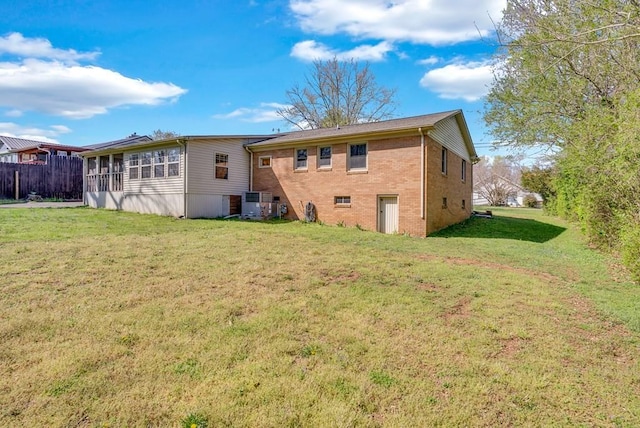 back of property with brick siding, fence, and a lawn