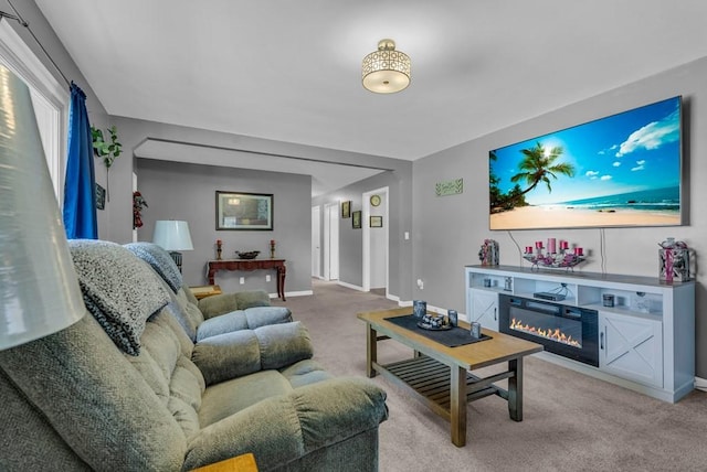 carpeted living room with baseboards and a glass covered fireplace