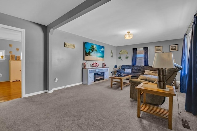 carpeted living area with visible vents, baseboards, and beamed ceiling