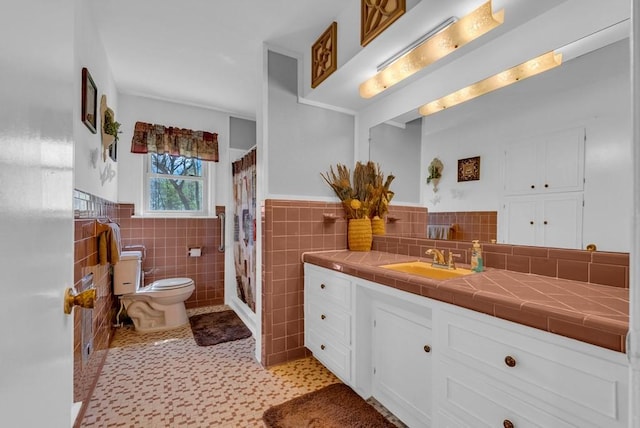 bathroom with vanity, tile walls, a wainscoted wall, and toilet