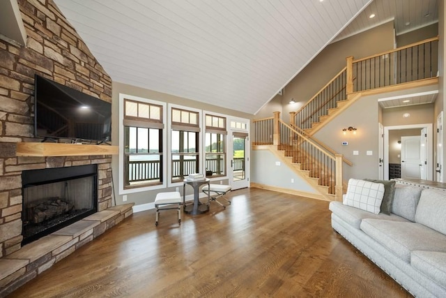 living area featuring stairway, a stone fireplace, baseboards, and wood finished floors