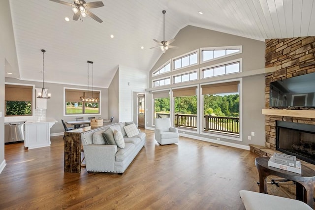 living area with a stone fireplace, baseboards, ceiling fan with notable chandelier, and wood finished floors