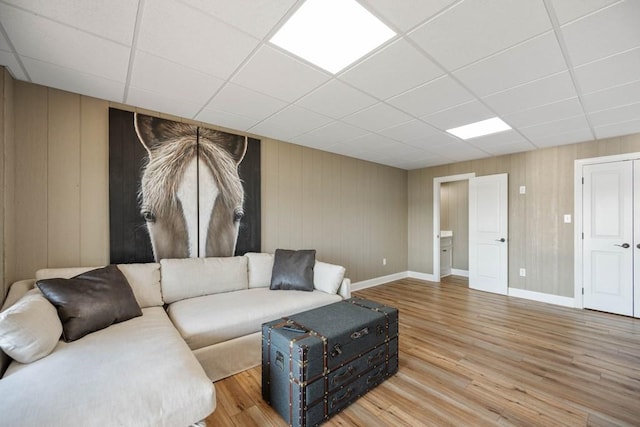 living room with a paneled ceiling, baseboards, and wood finished floors