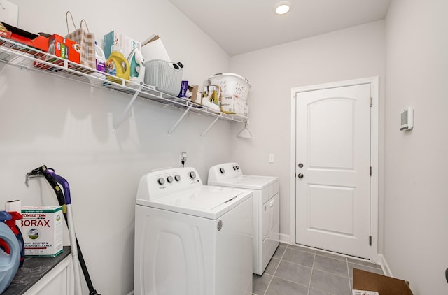clothes washing area featuring washer and clothes dryer, light tile patterned floors, laundry area, and baseboards