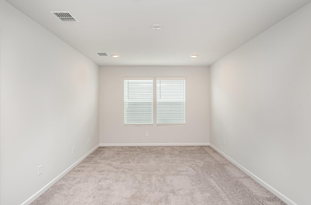 spare room featuring light colored carpet, baseboards, visible vents, and recessed lighting
