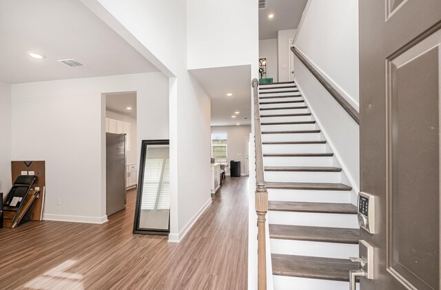 stairway featuring recessed lighting, visible vents, baseboards, and wood finished floors