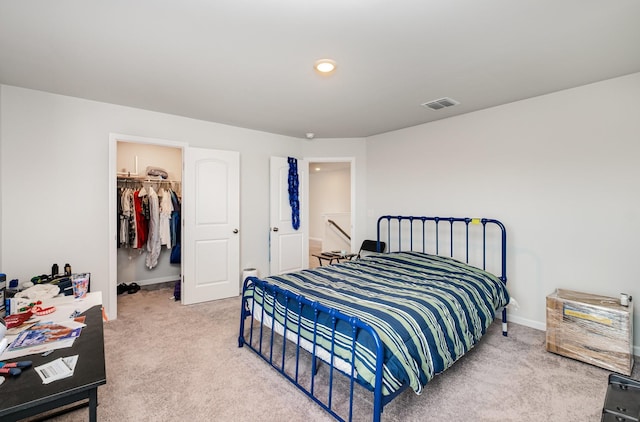 carpeted bedroom featuring a walk in closet, a closet, baseboards, and visible vents