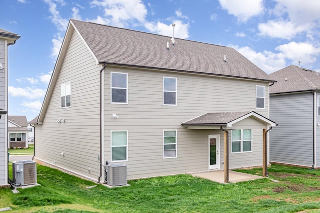 rear view of property featuring a patio, a shingled roof, central AC unit, and a lawn